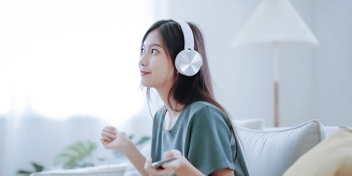 Woman sitting on a couch listening to music with wireless over-ear headphones