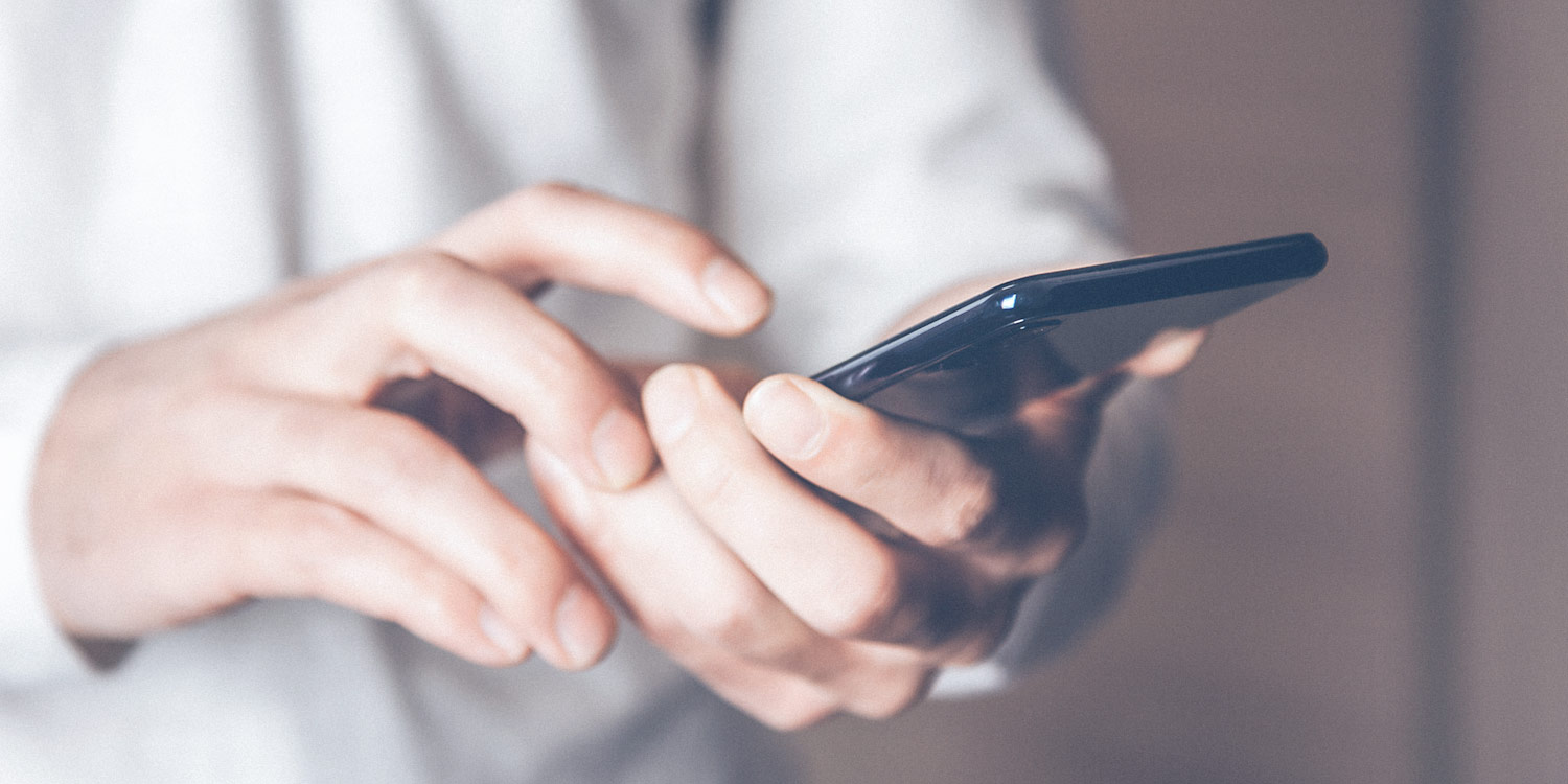 Close-up of young man holding black smartphone in hand