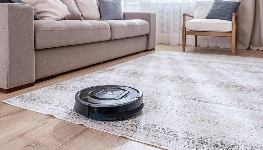 Robotic vacuum cleaner navigating off area rug onto hardwood floor